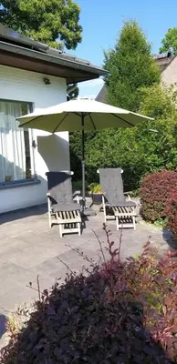 a group of chairs and an umbrella on a patio at logies Huis Liselotte in Genk