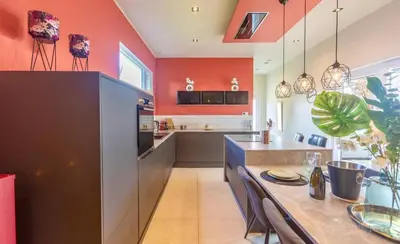 a kitchen with orange walls and a table with chairs at Charming 2-Bedroom House Rental in Dalhem, Belgium in Dalhem