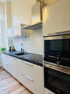 a kitchen with white cabinets and a black microwave at Appartement Premium à Liège in Liège