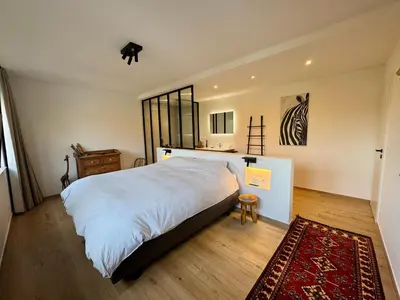 a bedroom with a large white bed and a rug at Au refuge des 3 pommes in Blégny