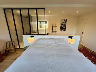 a large white bed in a room with windows at Au refuge des 3 pommes in Blégny