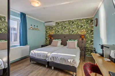 a bedroom with a bed and a desk with a computer at Hotel Brasserie de Klok in Zutendaal