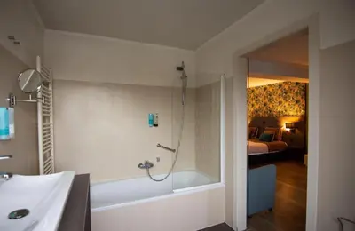 a bathroom with a shower and a bath tub at Hotel Brasserie de Klok in Zutendaal