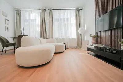 a living room with two white chairs and a television at Appartement en plein centre-ville in Liège