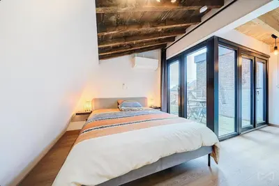 a bedroom with a large bed and large windows at Logement temporaire haut de gamme Particuliers & entreprises in Liège