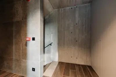 a room with a concrete wall and wooden floors at Coliving - Bord de Meuse - L'écrin Vert in Oupeye