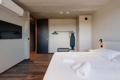 a bedroom with a white bed and a tv at Coliving - Bord de Meuse - L'écrin Vert in Oupeye