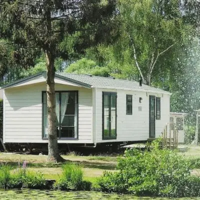 a small white house sitting next to a tree at Casa Nymphaea in Kinrooi