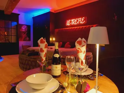 a table with a bottle of wine and wine glasses at Le Trèfle in Plombières