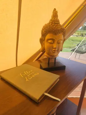 a statue of a head on a table with a book at Glamping met paarden in Nieuwerkerken