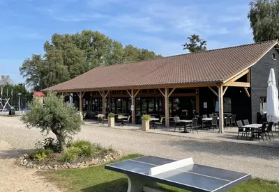 a pavilion with a table in front of a building at Camping Papillon Kinrooi - Pipowagen met terras in Kinrooi