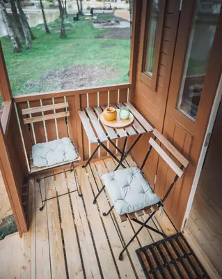 a porch with two chairs and a table with a plate of food at Camping Papillon Kinrooi - Pipowagen met terras in Kinrooi