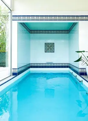 a swimming pool with blue tiles and a large window at Villa Bianca in Dalhem