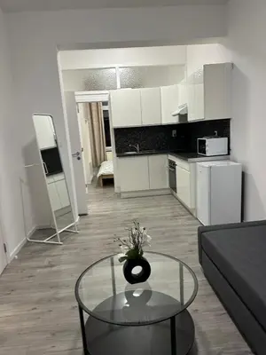 a living room with a glass table and a kitchen at 1 Chambre et Sofa Bed en plein cœur de Liege in Liège