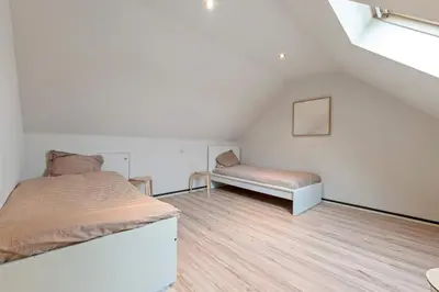 a bedroom with a bed and a bench in a attic at Ruime vakantievilla in Halen voor 12 personen in Halen