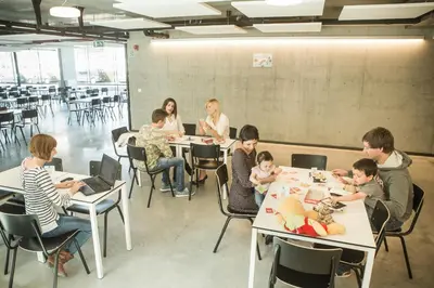 a group of people sitting at tables in a classroom at Hostel H in Hasselt