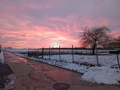 a snowy sidewalk with a sunset in the background at DE SMISHOEVE met kinderpret, dieren en wellness in Heers