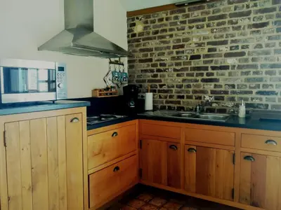 a kitchen with wooden cabinets and a brick wall at Vakantiewoning Venderhof in Maaseik