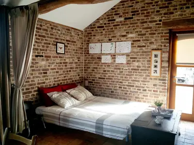 a bed in a room with a brick wall at Vakantiewoning Venderhof in Maaseik