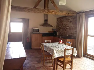 a kitchen with a table and chairs and a kitchen with a brick wall at Vakantiewoning Venderhof in Maaseik