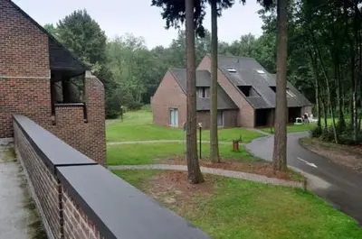 a view of a house with a fence and trees at Domein Hengelhoef in Houthalen-Helchteren