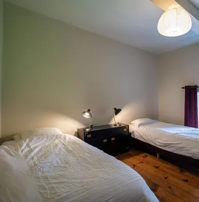 a bedroom with two beds and two lamps on a dresser at Kasteel Nieuwenhoven in Sint-Truiden