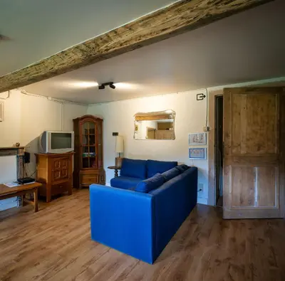 a living room with a blue couch and a tv at Kasteel Nieuwenhoven in Sint-Truiden