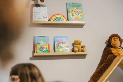 a woman sitting on a shelf with books and teddy bears at Green Resort Limburg in Houthalen-Helchteren