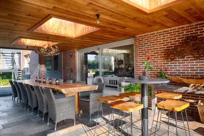 a patio with a table and chairs and a brick wall at Tussen Hemel en Maas in Dilsen-Stokkem