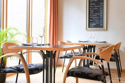 a dining room with two tables and chairs and a chalkboard at Sleepwood Hotel in Eupen
