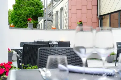 a table with chairs and wine glasses on a balcony at Sleepwood Hotel in Eupen