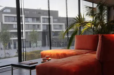 a living room with a couch and a large window at Hotel Corbie Lommel in Lommel
