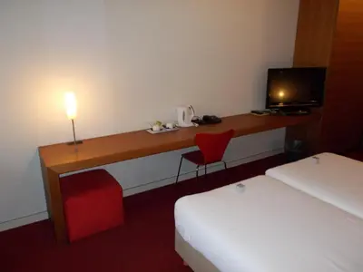 a hotel room with a desk and a red chair at Hotel Corbie Lommel in Lommel