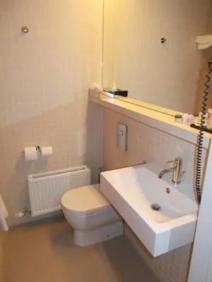 a bathroom with a white toilet and a sink at Hotel Corbie Lommel in Lommel