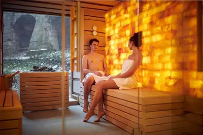 a man and a woman sitting in a sauna at Van Der Valk Sélys Liège Hotel & Spa in Liège