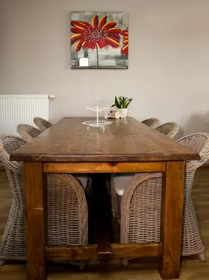 a wooden table with chairs and a painting on the wall at Bosbeekvallei in Opoeteren