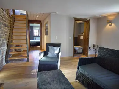 a living room with a couch and a staircase at Limbourg Nature Retreat in Hèvremont