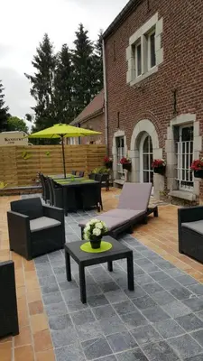 a patio with chairs and tables and an umbrella at le gite de zoelie in Chaineux