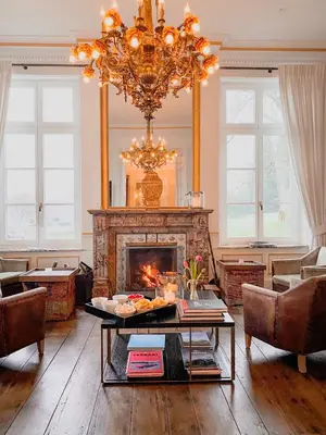 a living room with a fireplace and a chandelier at Château Charles in Pepinster