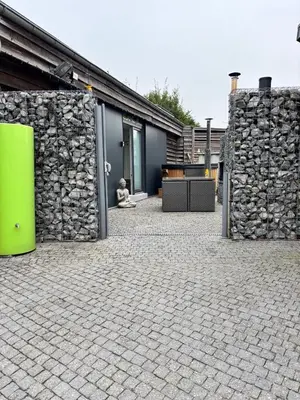 a building with a stone wall and a green object at Relax Trois Bornes - De Grenspost in Gemmenich