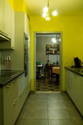 a kitchen with yellow walls and a dining room with a table at 't Gillebroek in Borgloon