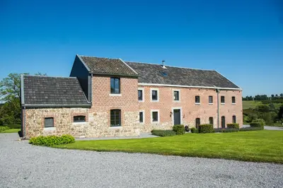 a large red brick house with a grass yard at En Vert & En Pause in Thimister