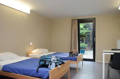a bedroom with two beds with a dog laying on a blanket at Hostel De Veurs in Sint-Martens-Voeren
