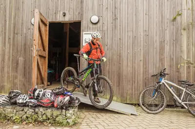a man is loading his bike into a building at Hostel De Veurs in Sint-Martens-Voeren