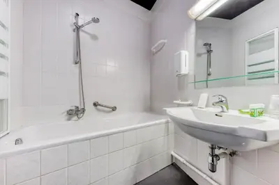 a white bathroom with a sink and a bath tub at Hôtel de la Gare in Visé