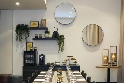 a dining room with a long table and a mirror at M Hotel in Genk