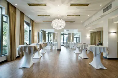 a banquet hall with white tables and chairs and a chandelier at M Hotel in Genk