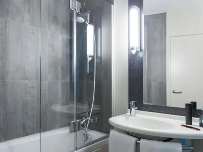 a bathroom with a sink and a glass shower at ibis Liège Centre Opéra in Liège