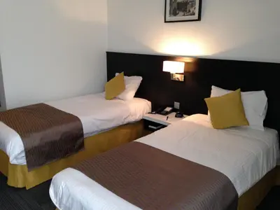 a hotel room with two beds with yellow pillows at Globales Post Hotel & Wellness in Herstal