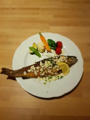 a plate of fish with vegetables on a table at Hotel Restaurant The Kings Head Inn in Voeren